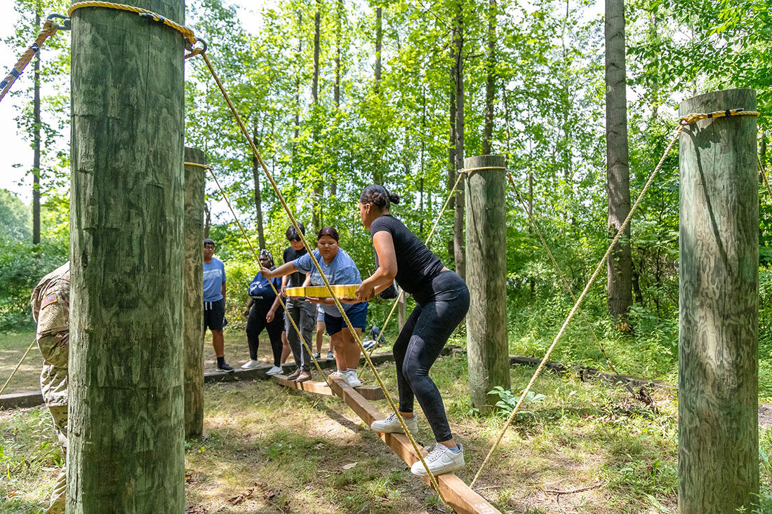 Four CoB Summer Leadership Academy students leaning on a wood beam