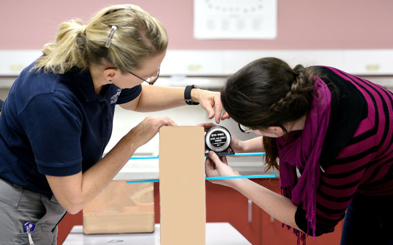 Forensics Lab faculty member, Brenda Butler, showing her student how to check a bullet hole's direction.