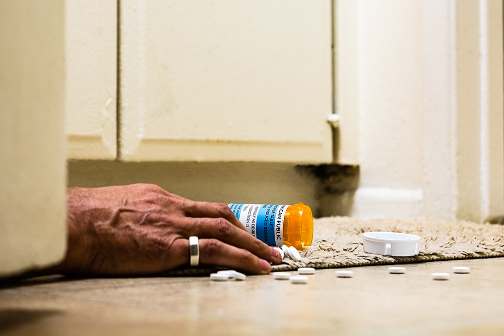 A pill bottle on its side, with the contents spilled about it